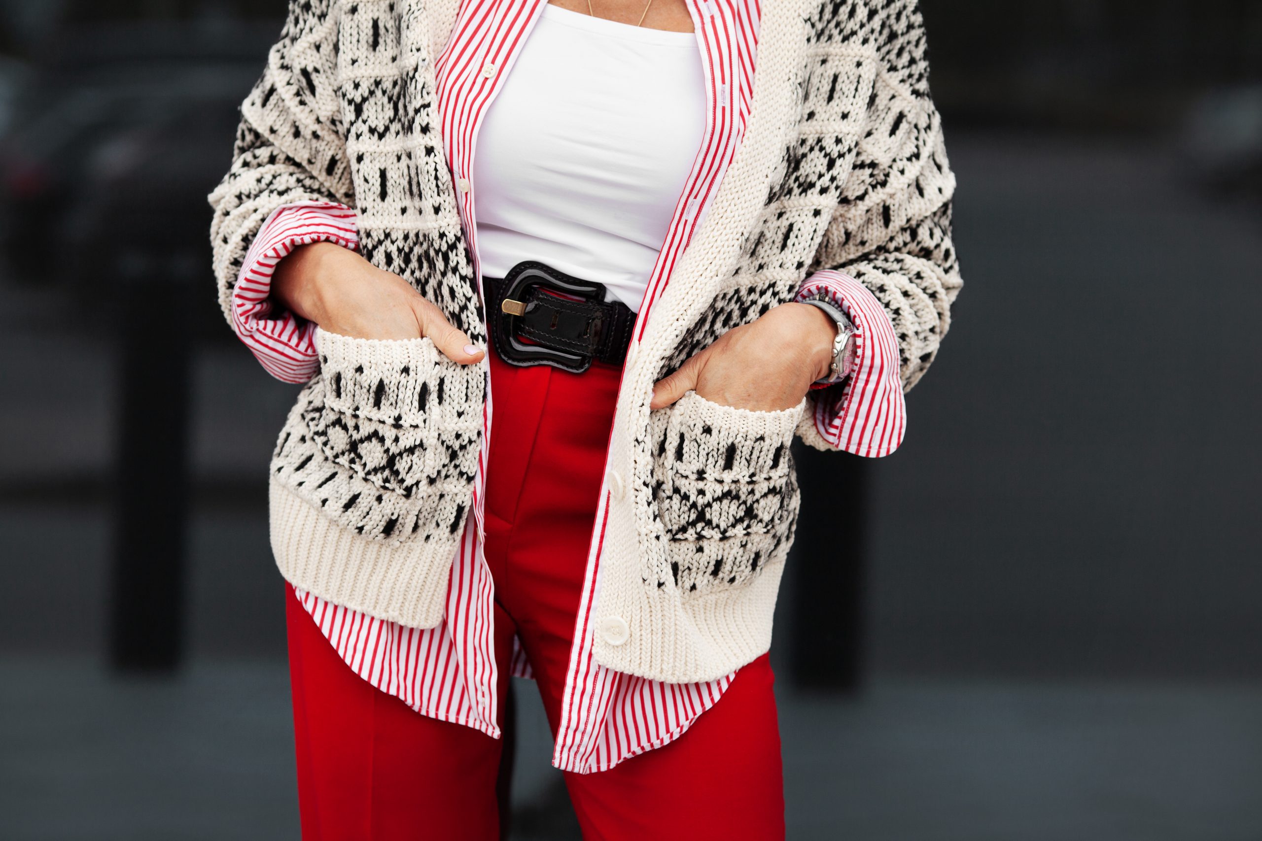Street style details. Close up hands in pockets of stylish woman. Fashion blogger wearing sweater, shirt, belt and pants. Autumn or spring fashion trend